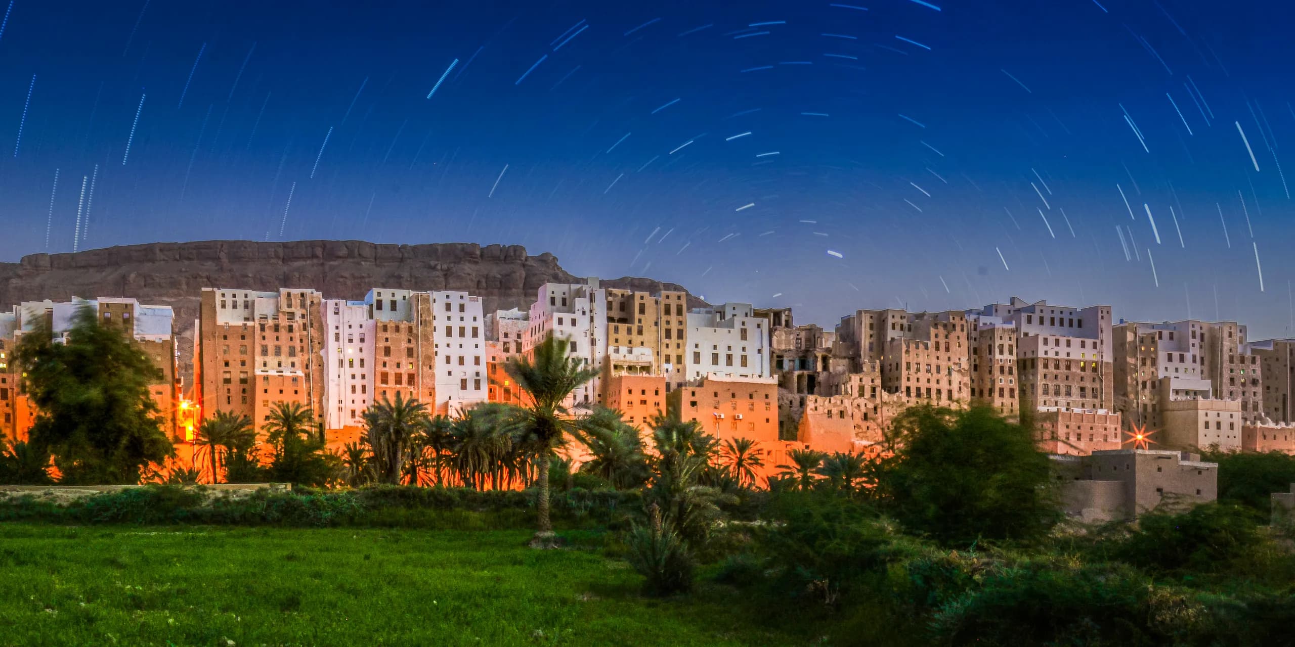 مدينة شبام في حضرموت ببيوتها الطينية العالية ليلاً، ومسارات النجوم في السماء فوقها